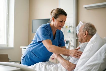 Aide-soignante en scrubs bleus aidant un patient âgé