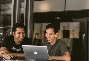 two smiling men looking at MacBook