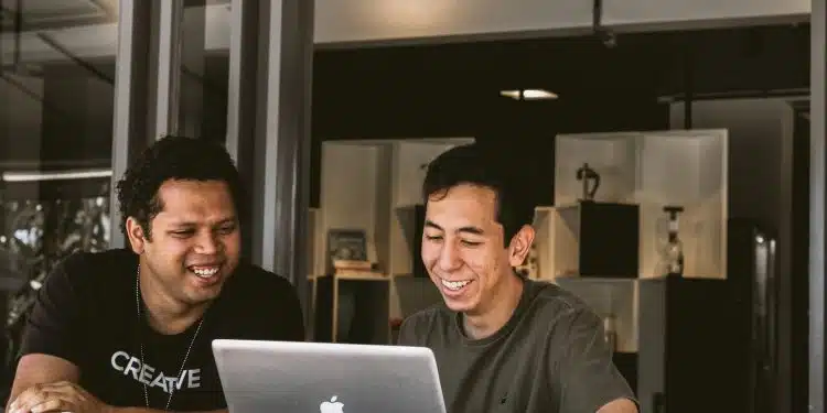 two smiling men looking at MacBook